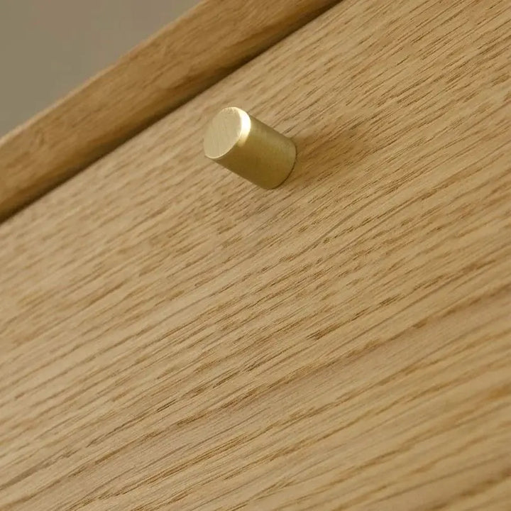 Detalje af guldfarvet knap på egetræsskab med naturlig overflade. Dansk design, produceret i Europa.